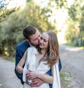 groom embracing bride from behind and giving her a kiss on the cheek, bride is smilling