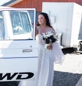 bride holding flowers opening door to wedding car